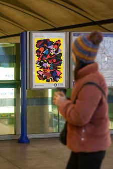 A poster of the 33rd pocket Tube map cover by Phyllida Barlow is seen by a member of the public in a station.